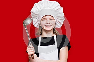 Happy little girl in chef uniform holds spoon isolated on red