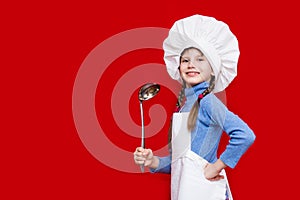 Happy little girl in chef uniform holds spoon on red