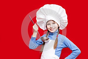 Happy little girl in chef uniform holds spoon on red. Kid chef. Cooking Concept