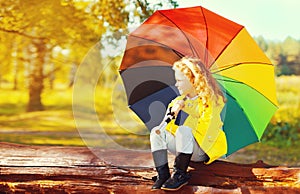 Happy little girl child with colorful umbrella in sunny autumn park