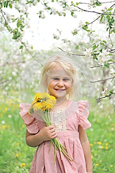 Happy Little Girl Child Holding Flowers Under the Apple Trees