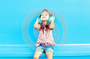 Happy little girl child listens to music in headphones