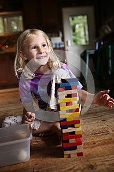 Happy Little Girl Child Playing with Blocks and Building a Tower