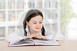 Happy little girl child reads book indoor