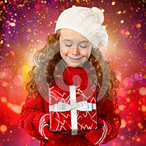 Happy little girl with Christmas gift over lights background