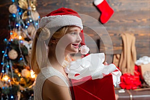 Happy Little girl with a Christmas present on wooden background. Christmas children. Joyful teenager looking at camera