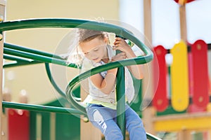 Happy little girl climbing on children playground