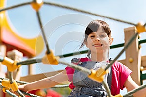 Happy little girl climbing on children playground