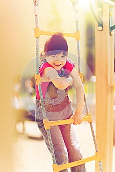 Happy little girl climbing on children playground