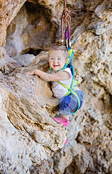 Happy little girl climbing on cliff