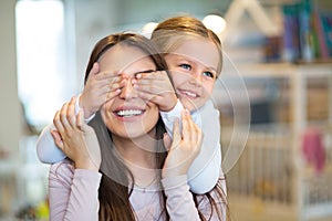 Happy little girl cover her mother eyes