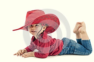 Happy little girl cowboy in a red hat on a white