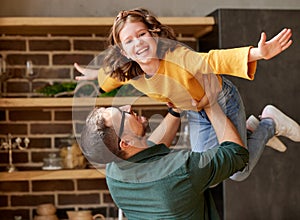 Happy little girl daughter playing with daddy at home, flying in air in fathers arms