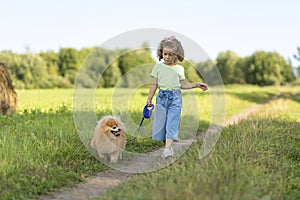 Happy little girl with dog running in park, summer field. child playing with puppy outdoors.
