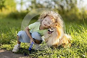 Happy little girl with dog running in park, summer field. child playing with puppy outdoors.