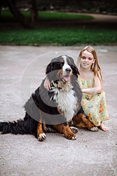 Happy little girl with a dog standing on the road in the park. Cute little girl hugging a dog, smiling. Child with dogs.