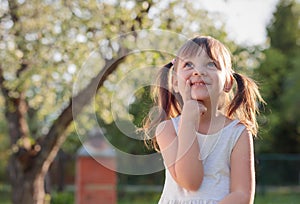 Happy little girl dreaming in the garden