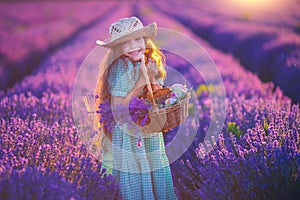 Happy little girl with dress enjoying lavender field with bouquet of flowers