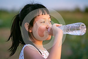 Happy little girl drinking pure water.Concept of healthy life photo