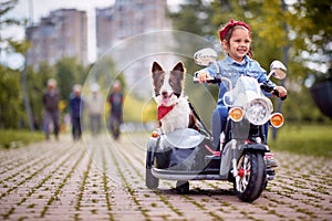 Happy little girl driving in a toy motocycle