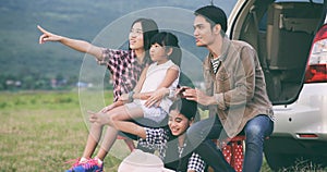 Happy little girl e with asian family sitting in the car for enjoying road trip and summer vacation in camper van