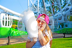 Happy little girl eating cotton candy outdoor