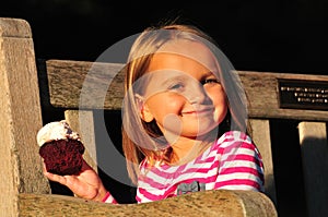 Happy little girl eating a cupcake