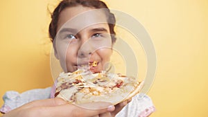 Happy little girl eating a slice of pizza concept. Teenager child hungry eats a slice of pizza. Slow motion video. Pizza