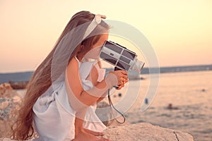 Happy Little Girl Enjoying Sea Sunset and Beach Using Retro Camera