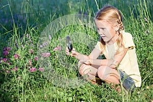 Happy little girl exploring nature with magnifying glass