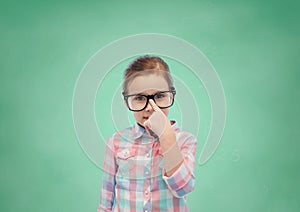 Happy little girl in eyeglasses over school board