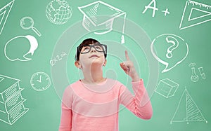 Happy little girl in eyeglasses pointing finger up