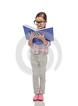 Happy little girl in eyeglasses reading book