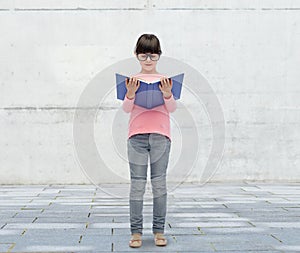 Happy little girl in eyeglasses reading book