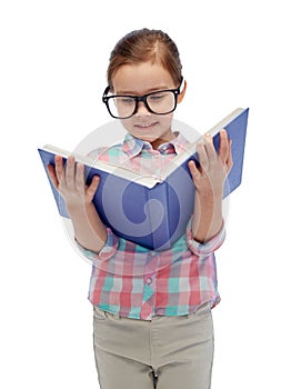 Happy little girl in eyeglasses reading book