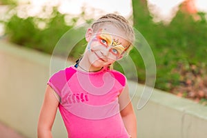 Happy little girl with face art paint in the park.