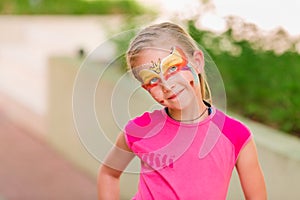 Happy little girl with face art paint in the park.