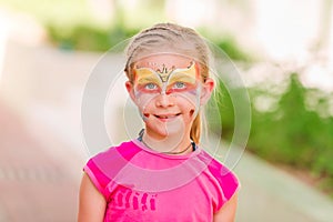 Happy little girl with face art paint in the park.