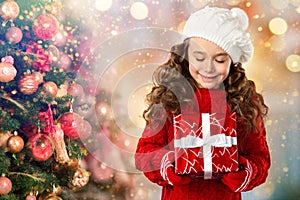 Happy little girl with gift near Christmas tree