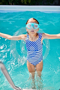 Happy Little girl in goggles having fun, dives and swim in the swimming pool