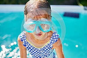 Happy Little girl in goggles having fun, dives and swim in the swimming pool