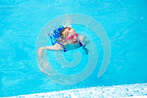Happy little girl in goggles playing in swimming pool Beach resort, summer vacation, travel and tourism concept