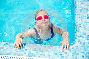 Happy little girl in goggles playing in swimming pool Beach resort, summer vacation, travel and tourism concept