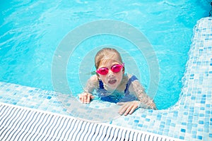 Happy little girl in goggles playing in swimming pool Beach resort, summer vacation, travel and tourism concept