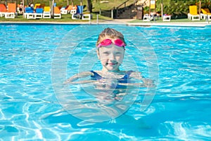 Happy little girl in goggles playing in swimming pool Beach resort, summer vacation, travel and tourism concept