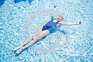 Happy little girl in goggles swim in swimming pool View from above