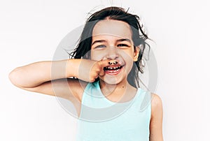 Happy little girl grimacing and smiling broadly with mustache drawing on her index finger put it on the mouth. Adorable child