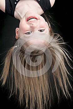 Happy little girl hanging upside down isolated on