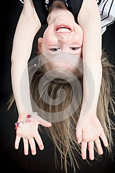 Happy little girl hanging upside down isolated on