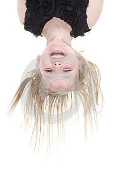 Happy little girl hanging upside down isolated on